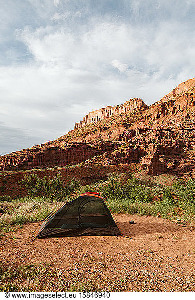 black tent without rain fly set up beneath red rocks near moab utah