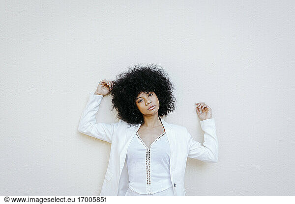 Black womam  wearing white suit  leaning on white wall