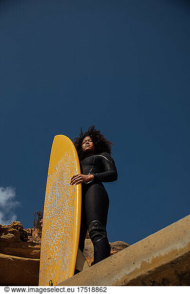 Black Woman carrying a surfboard