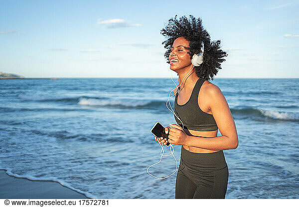 black woman laughing and having fun dancing by the sea