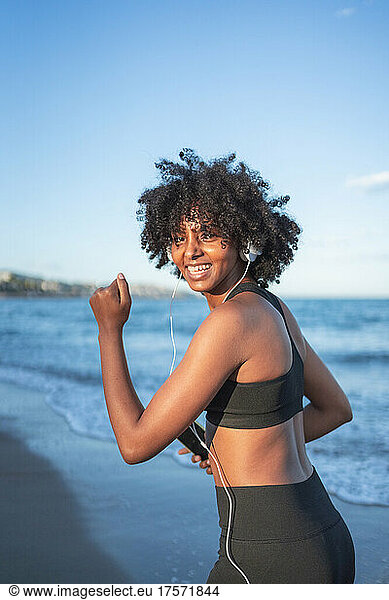 black woman laughing and having fun listening to music on the beach