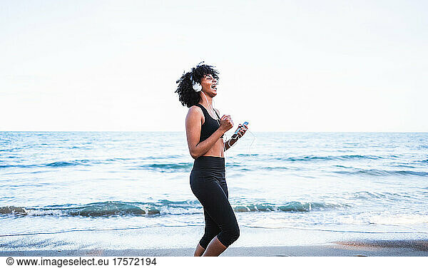 black woman laughing and having fun listening to music on the beach