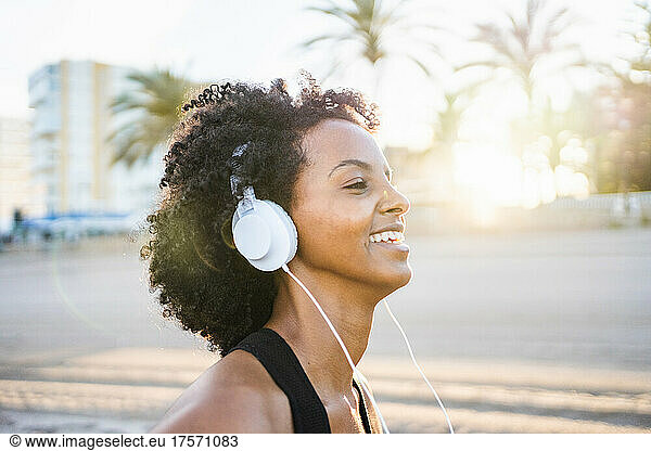 black woman with afro hair dances listening to music on the beach