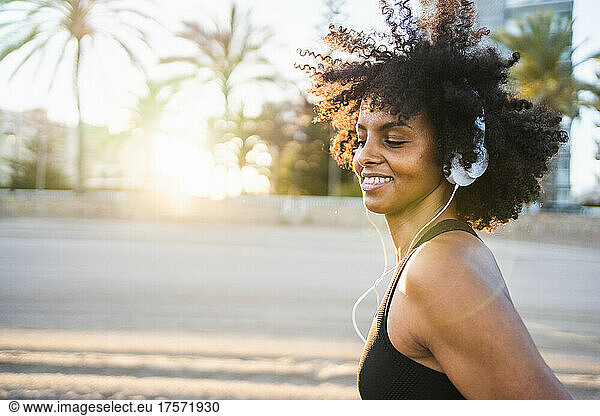 black woman with afro hair dancing listening to music on the beach