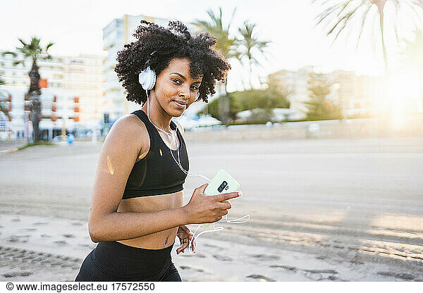 black woman with afro hair runs confident on the beach