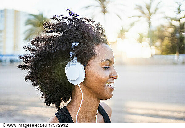black woman with afro hair runs listening to music at sunrise