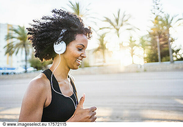 black woman with afro hair runs listening to music on the beach