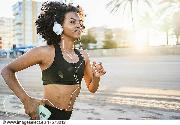 black woman with afro hair runs listening to music with her mobile