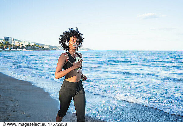 black woman with afro hair runs listening to music with the mobile