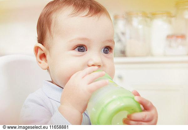 Blauäugiger Babyjunge trinkt aus der Babyflasche