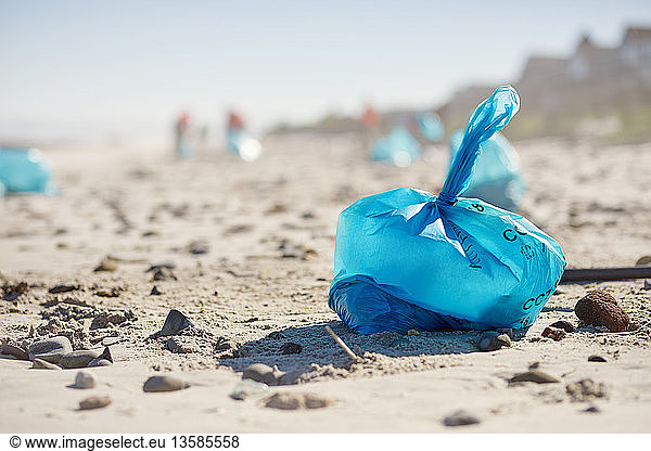 Blauer Müllsack am sonnigen Sandstrand