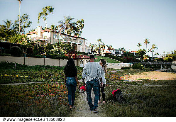 Blended family with dogs walks on beach trail at sunset