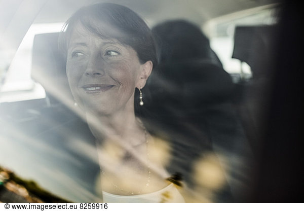 Blick auf die lächelnde Geschäftsfrau beim Blick aus dem Taxi-Fenster