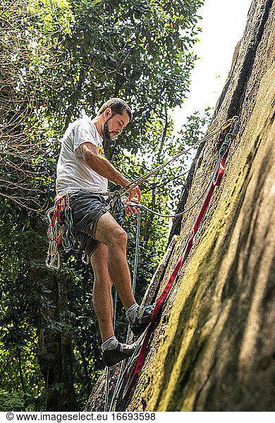 Blick auf einen Mann beim Klettern an einer Felswand im Regenwald