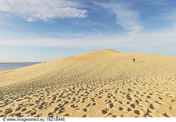 Blick auf einen Mann  der auf einer Sanddüne gegen den Himmel läuft  Düne von Pilat  Nouvelle-Aquitaine  Frankreich