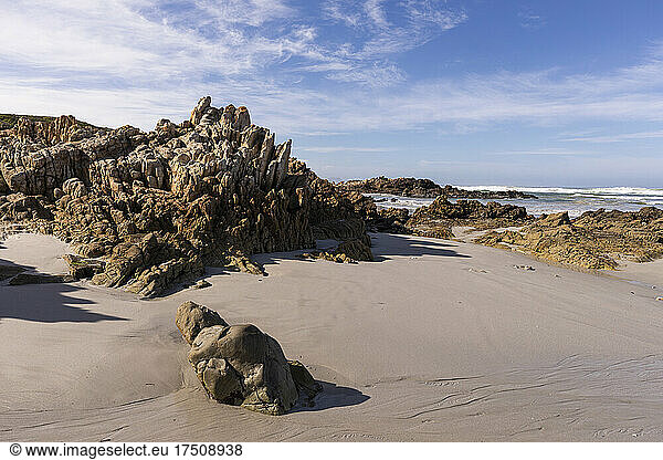 Blick auf einen Sandstrand und Felsformationen an der Atlantikküste.