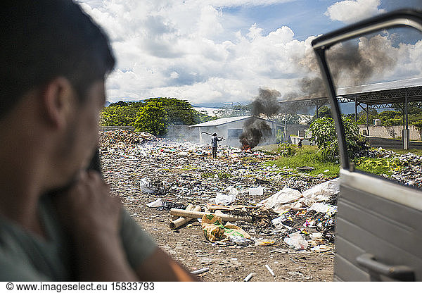 Blick aus dem Fahrzeug eines Arbeiters auf eine brennende Mülldeponie.