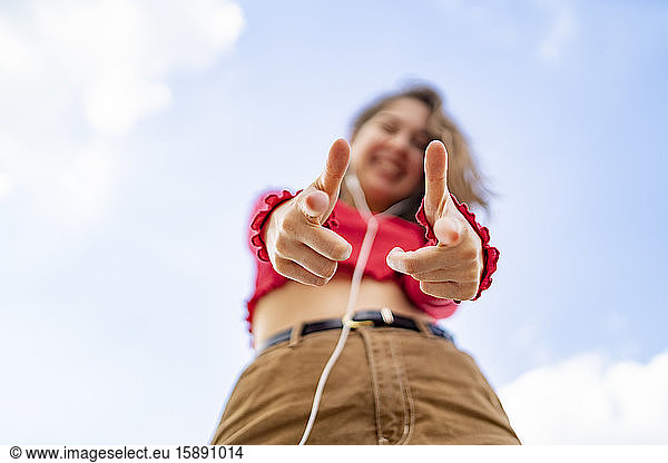 Blick aus der Froschperspektive auf eine junge Frau  die mit Kopfhörern Musik hört