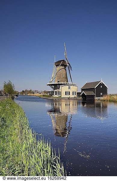 Blick über den Fluss Graafstroom auf die Windmühle De Vriendschap im Dorf Bleskensgraaf an einem klaren und frischen Frühlingstag.