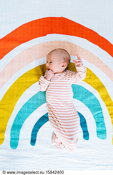 Blick von oben auf ein Neugeborenes auf einer regenbogenfarbigen Decke