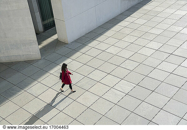 Blick von oben auf eine gehende moderne Geschäftsfrau auf einem Betonboden
