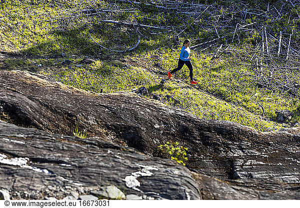Blick von oben auf eine starke Sportlerin  die beim Fitnesstraining auf dem Lande einen Bergpfad entlangläuft