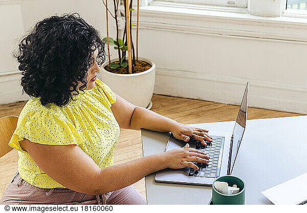 Blick von oben auf eine Unternehmerin  die auf einem Laptop tippt