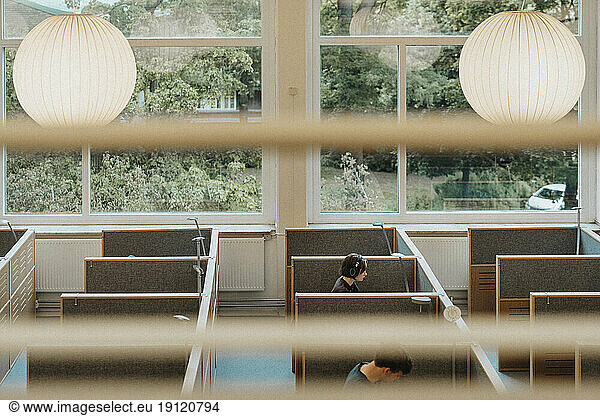 Blick von oben auf männliche und weibliche Studenten  die in der Bibliothek einer Universität lernen