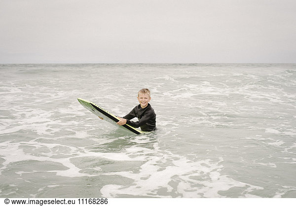 Blond boy bodyboarding in the ocean.