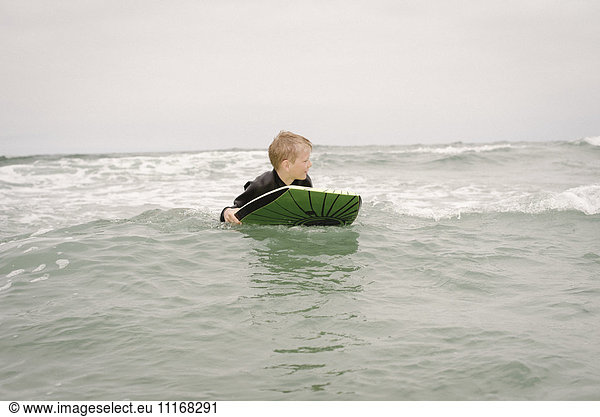 Blond boy bodyboarding in the ocean.