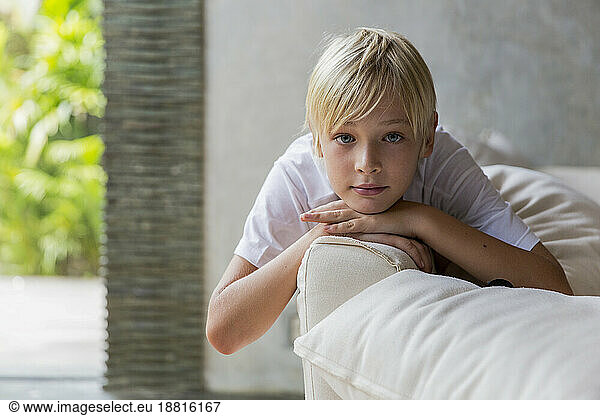 Blond boy lying on sofa at home