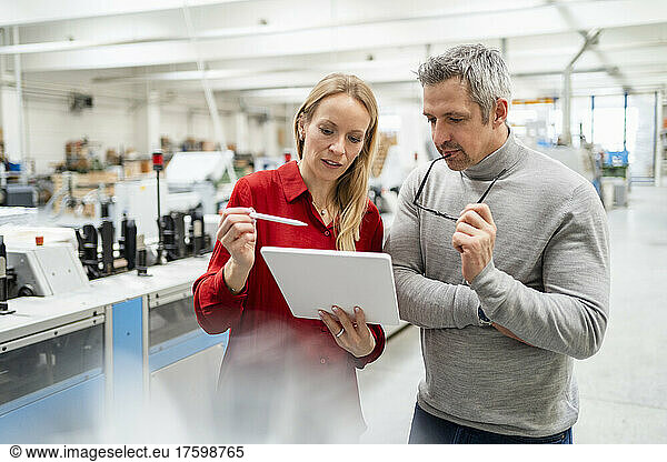 Blond businesswoman discussing over tablet PC with businesswoman in industry