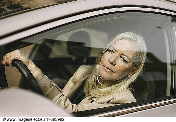 Blond businesswoman looking through car window