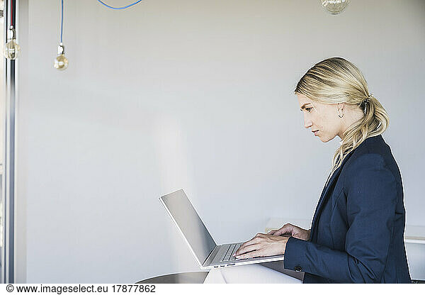 Blond businesswoman using laptop in office