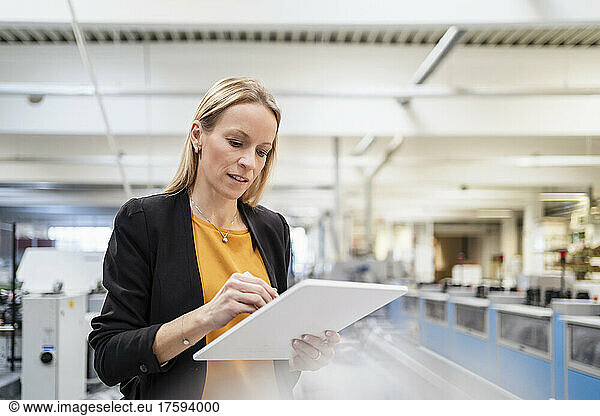 Blond businesswoman using tablet PC in factory