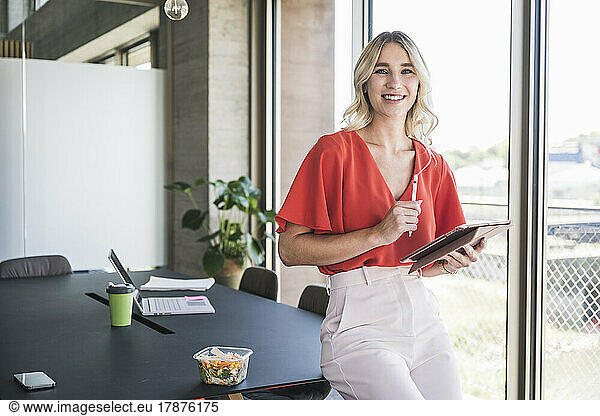 Blond businesswoman with digitized pen and tablet PC in office