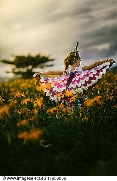 Blond female child with butterfly wings in orange flower field