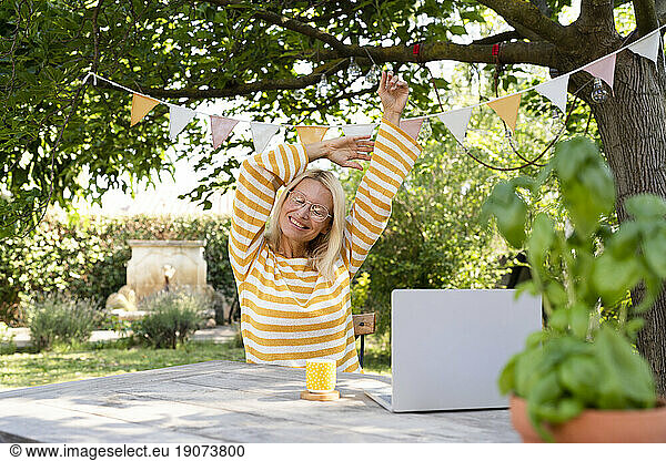Blond freelancer stretching at table in garden