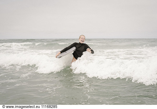 Blond girl bodyboarding in the ocean.