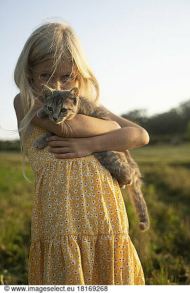 Blond girl carrying cat on sunny day