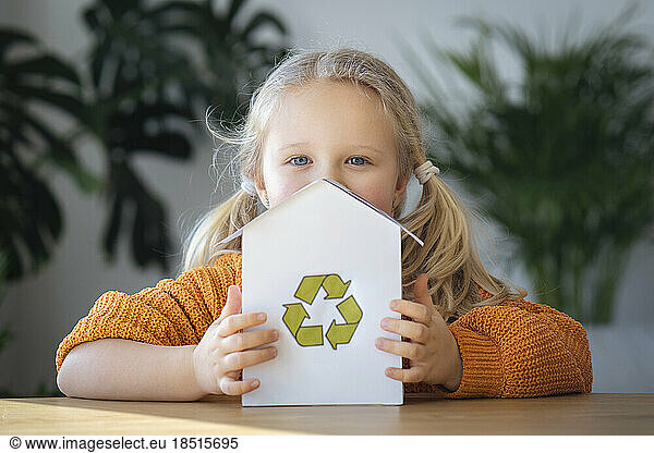 Blond girl holding house model with recycling logo