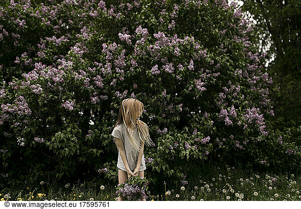 Blond girl in front of fresh flowers in nature