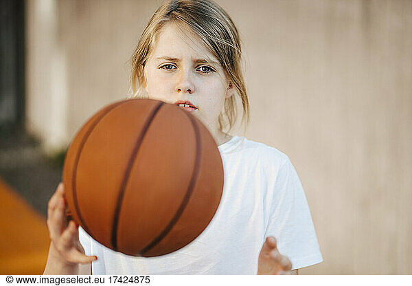 Blond girl playing with ball at basketball court