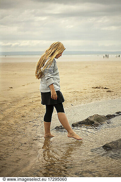 Blond girl playing with puddle at beach Blond girl playing with puddle ...