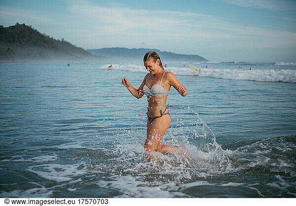 blond girl running out of the ocean in Costa Rica