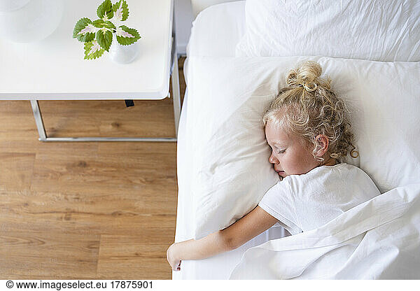 Blond girl sleeping in bed at home