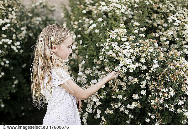 Blond girl touching white flowers