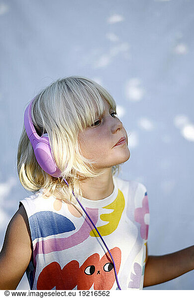 Blond girl wearing headphones and listening to music