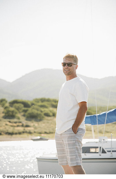 Blond man wearing sunglasses standing on a jetty.