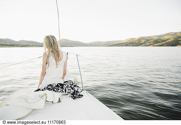 Blond teenage girl sitting on sail boat.